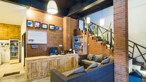 Una recepción con pared de ladrillo, mostrador de madera, sofá y escalera.