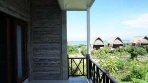 Un balcón con vistas a bungalows sobre el agua y exuberante vegetación.