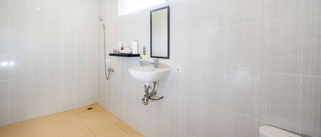 Un baño moderno con azulejos blancos, un lavabo, un espejo y un inodoro.