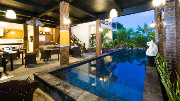 Una piscina interior con pared de ladrillo y una escalera que lleva a un nivel superior.
