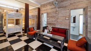 Habitación de hotel con piso a cuadros, un sofá, una mesita de centro y una cama litera.