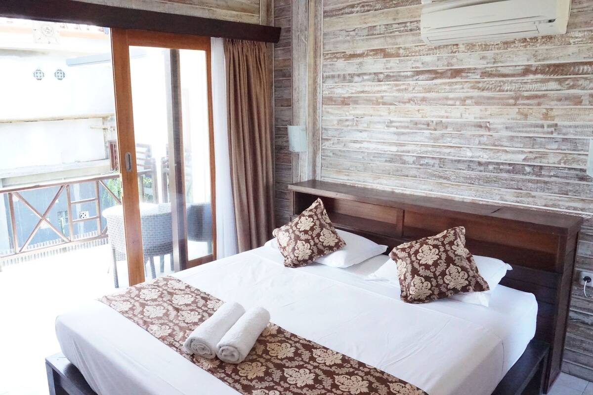Habitación de hotel con cama, dos almohadas, una ventana y vistas al exterior.