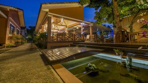 Un patio con fuente de agua, puente de madera y zona de estar al aire libre.
