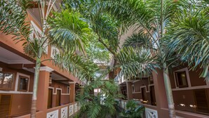 Un atrio de varios niveles con un jardín central, rodeado por balcones con barandillas y ventanas.