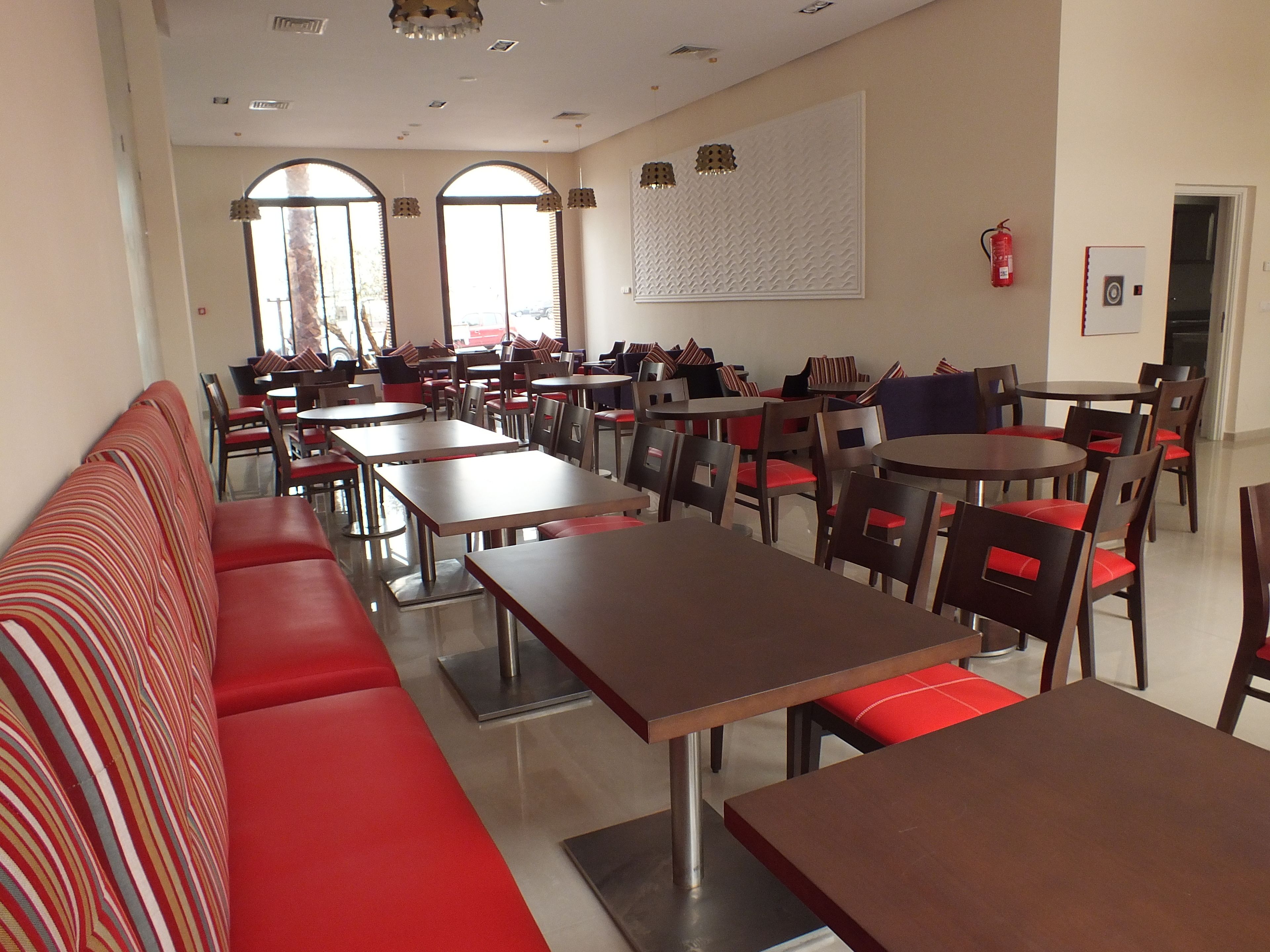 Un restaurante con varias mesas y cabinas, asientos acolchados en rojo y ventanas amplias.