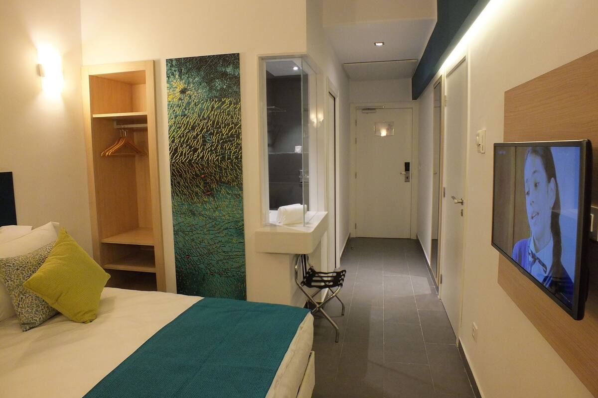 A hotel room with a bed, a closet, a bathroom, and a TV.