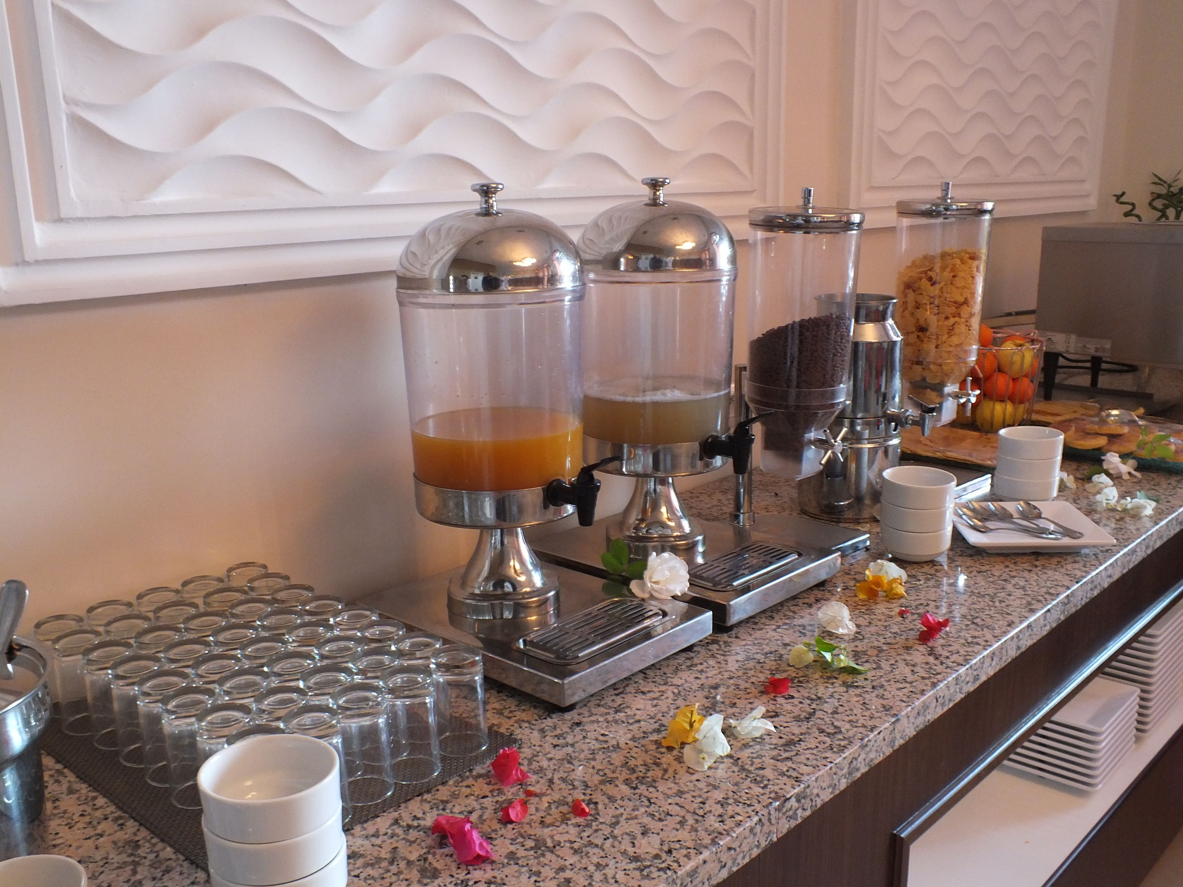 Un buffet proposant une variété de boissons en libre-service, une présentation de fruits et un assortiment de plats.
