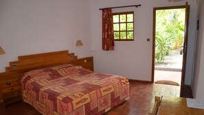 Un dormitorio con una cama de madera, una ventana con cortinas y vistas al exterior.