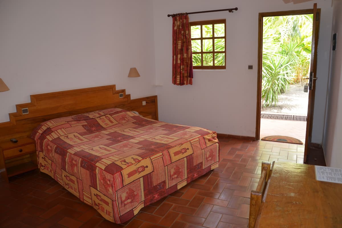 Un dormitorio con una cama de madera, una ventana con cortinas y vistas al exterior.