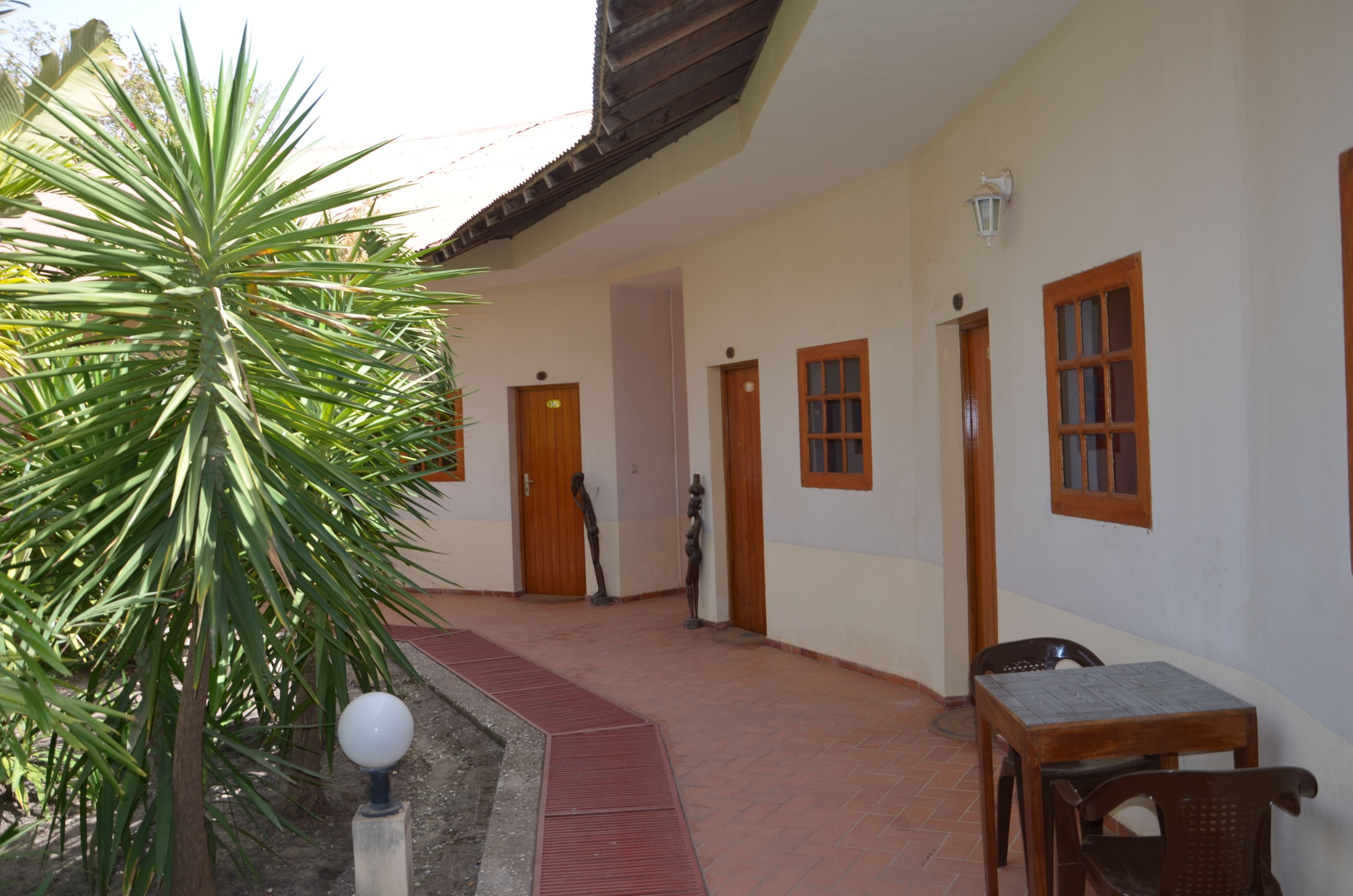 Uma área externa coberta com uma palmeira, uma mesa e cadeiras.