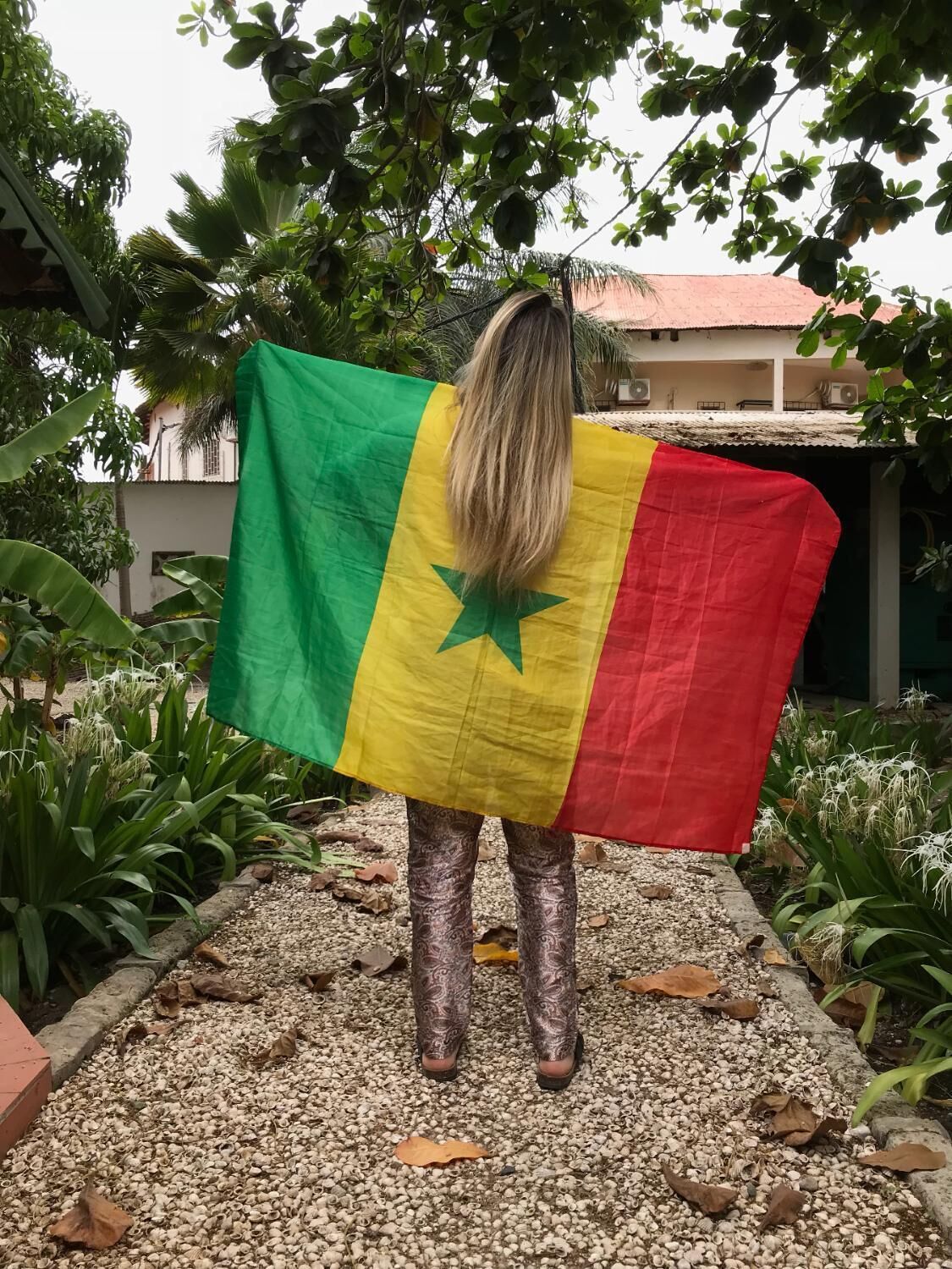 A person standing in a garden with a flag.