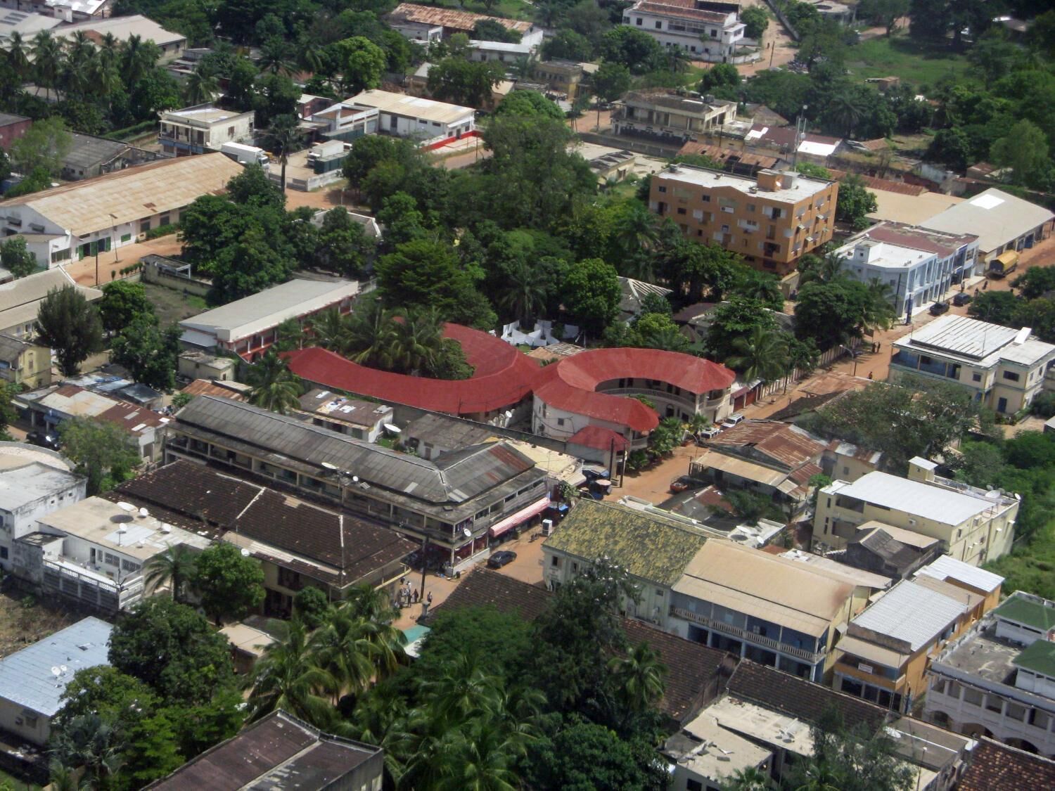 An aerial view of a densely built urban area with various buildings, including a prominent structure with a red roof.