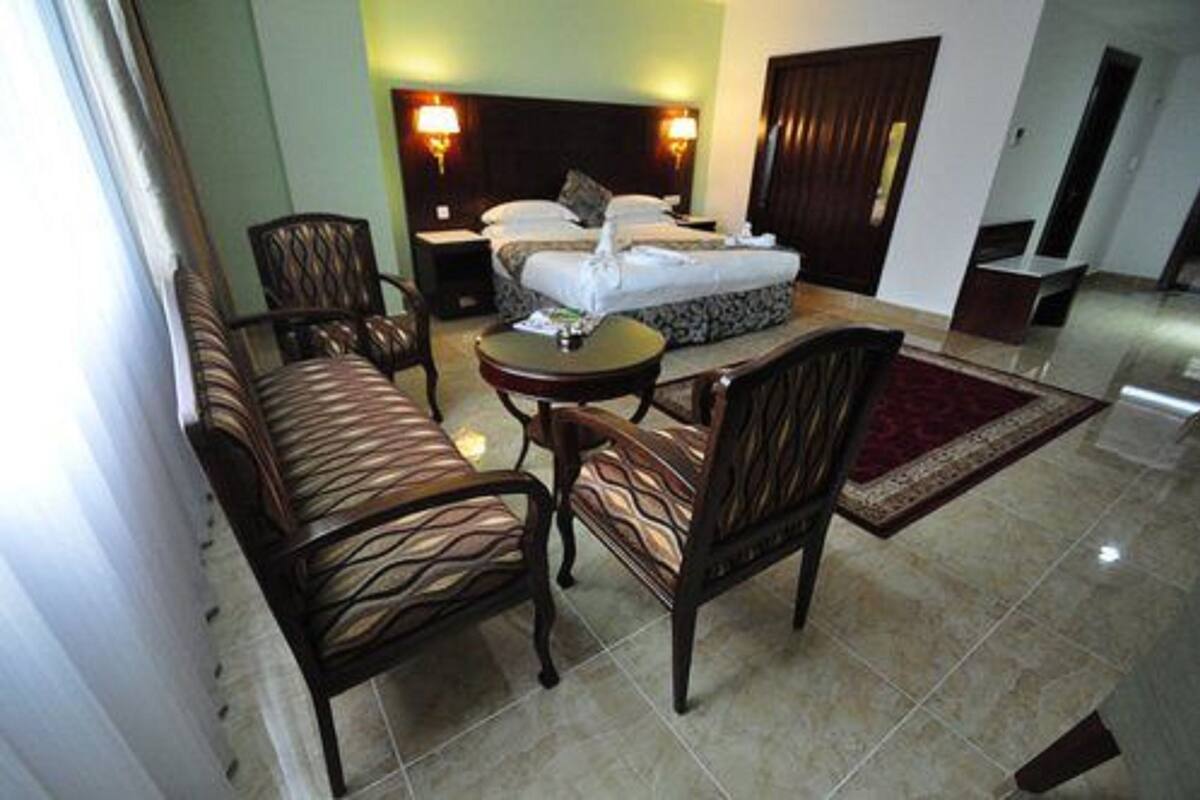 Une chambre d’hôtel avec un lit, un canapé, une table et deux chaises.