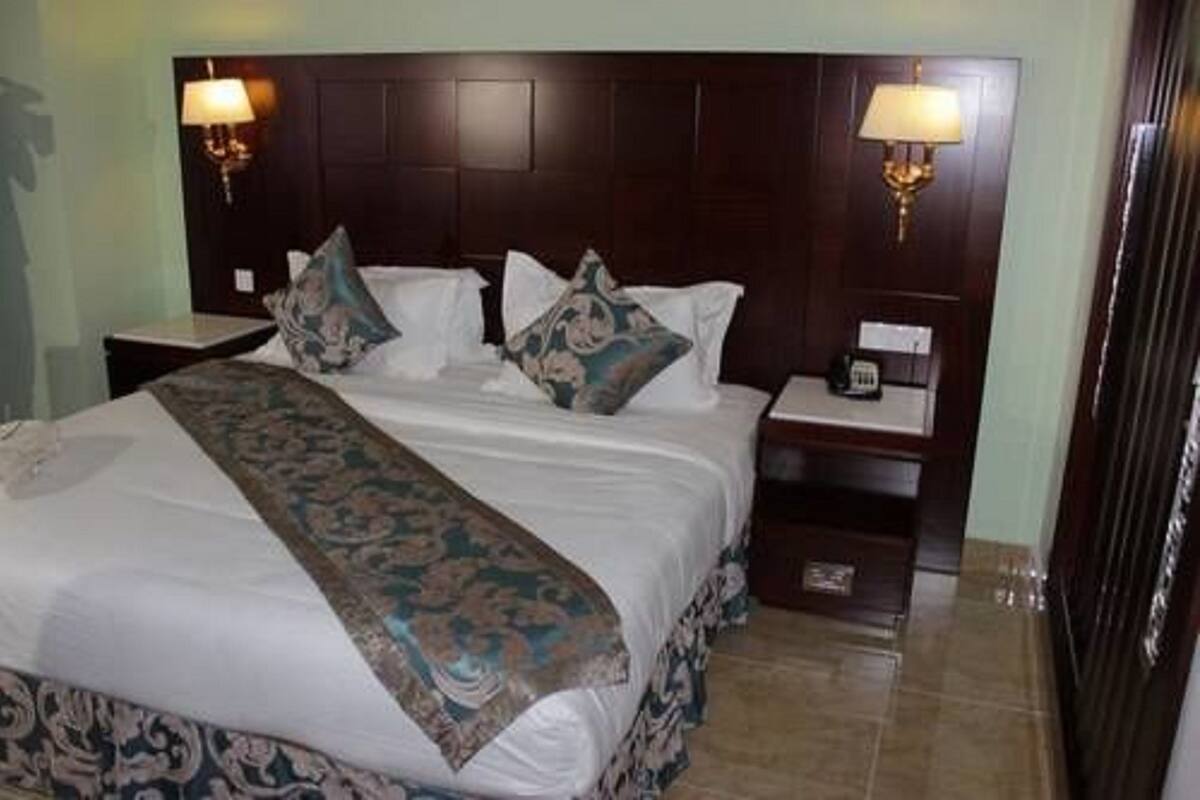 Une chambre d’hôtel avec un grand lit, deux tables de chevet, une petite table et une lampe.