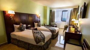 A hotel room with two beds, a desk, and a chair. - Soltane Hotel (Algiers)