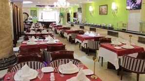 A restaurant with multiple tables set for dining, each with white tablecloths and red napkins. - Soltane Hotel (Algiers)