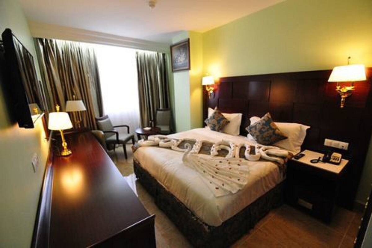 Une chambre d’hôtel avec un grand lit, deux tables de chevet avec des lampes, un bureau et une chaise.