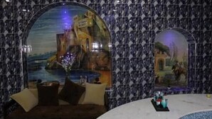 A room with a round table, two sofas, and a large arched window with a cityscape view. - Soltane Hotel (Algiers)