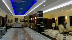 A hotel lobby with a marble floor, a reception desk, and a seating area with chairs and a sofa. - Soltane Hotel (Algiers)