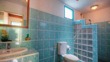 A bathroom with blue tiles, a white sink, a toilet, and a shower enclosure.