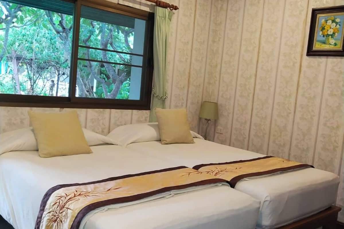 Uma cama de casal com cabeceira de madeira, dois travesseiros e uma mesa de cabeceira com abajur.