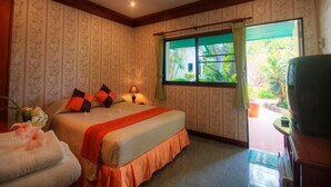 A bedroom with a bed, a window with curtains, a nightstand, and a chair.