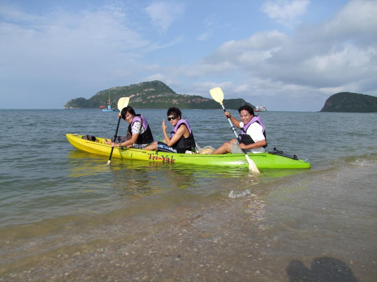 Two people kayaking on a calm body of water with a distant island in the background.