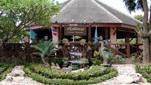 A restaurant with a sign reading "Chomlay Restaurant" surrounded by tropical plants and a decorative water feature.