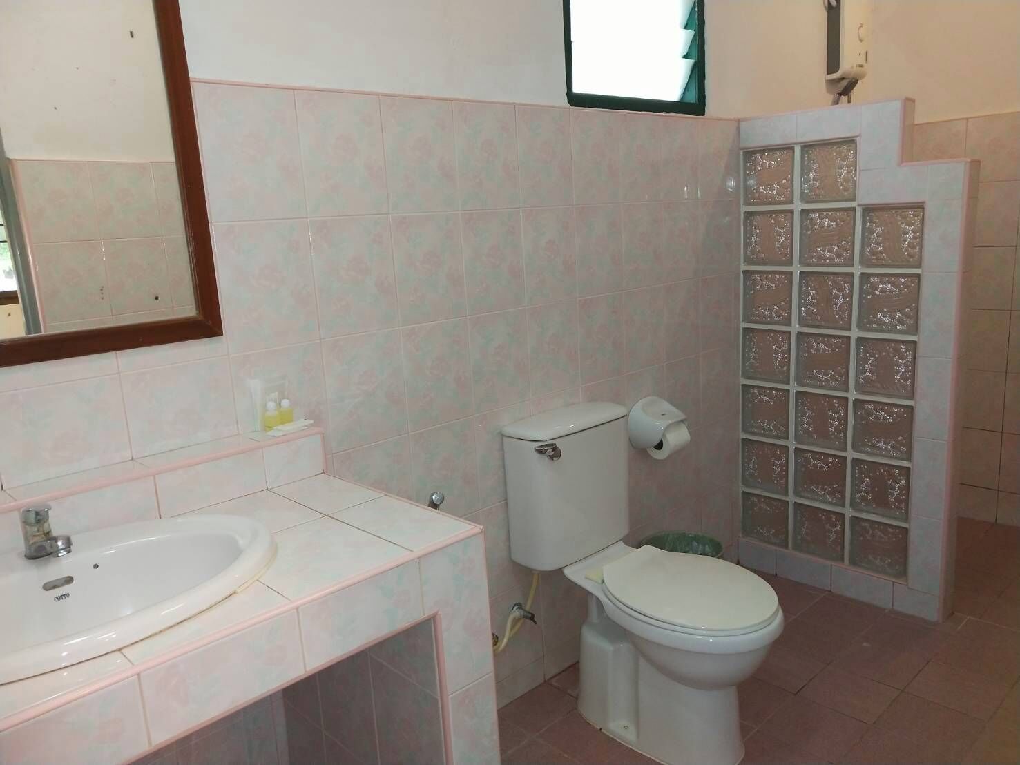 Ein Badezimmer mit Waschbecken, Toilette und Duschbereich mit Glaswänden.