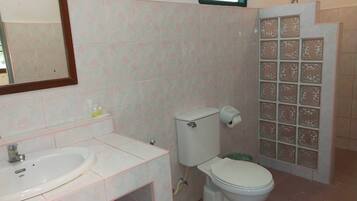 Ein Badezimmer mit Waschbecken, Toilette und Duschbereich mit Glaswänden.