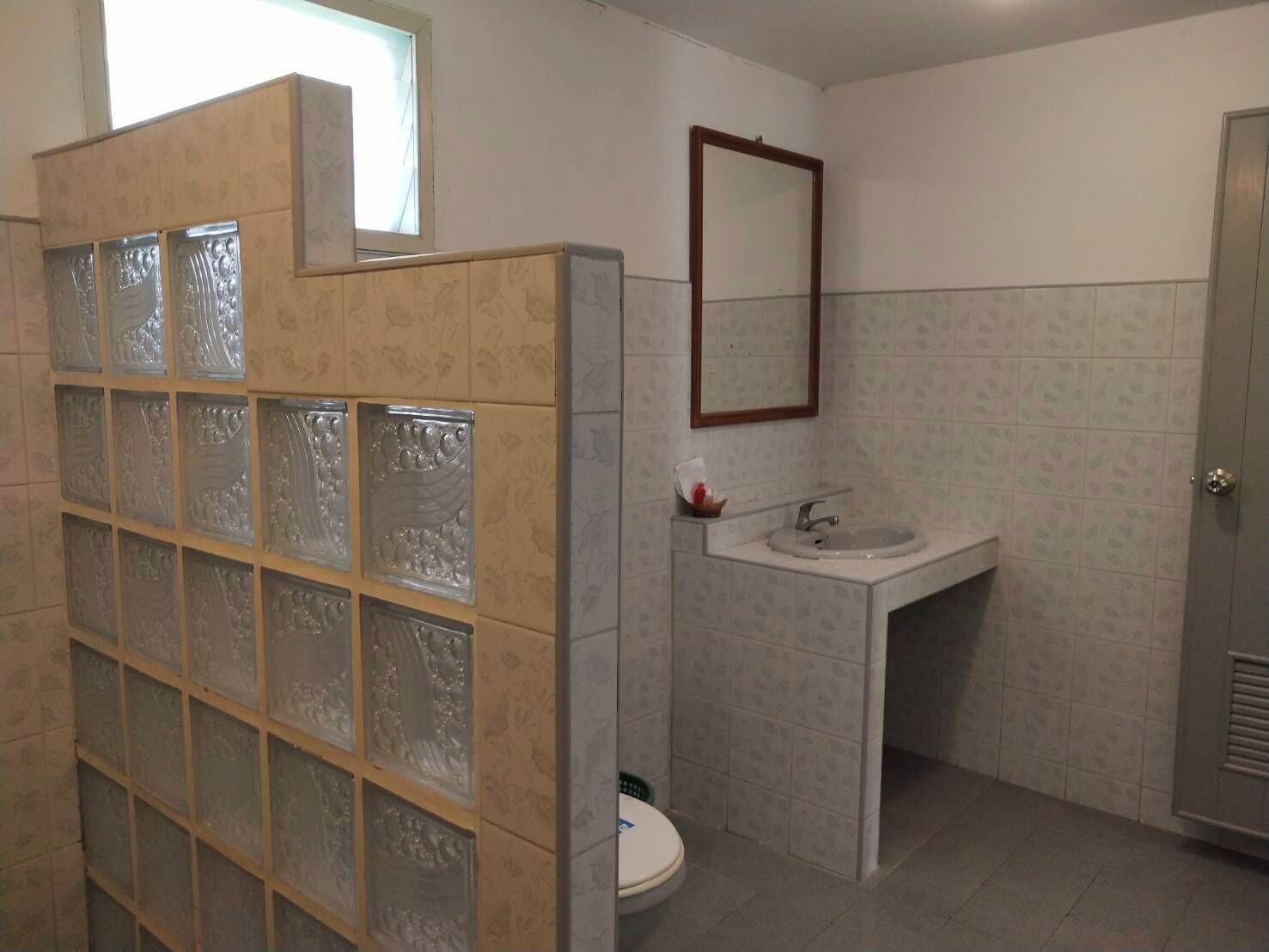 Un baño con inodoro, lavamanos y cabina de ducha con cristal satinado.