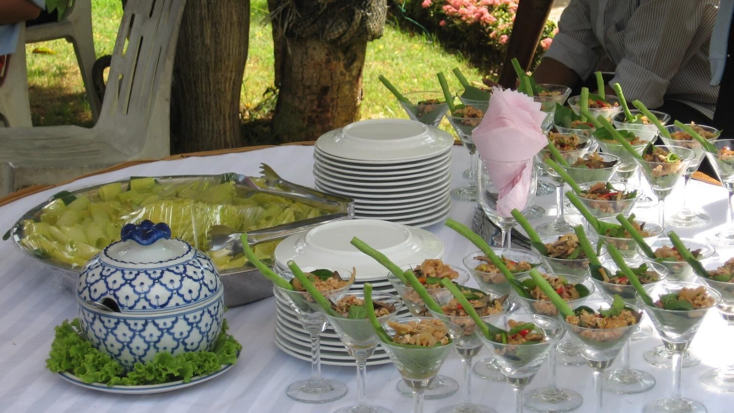 Una mesa de buffet con varios platos y un recipiente decorativo de cerámica azul y blanco.
