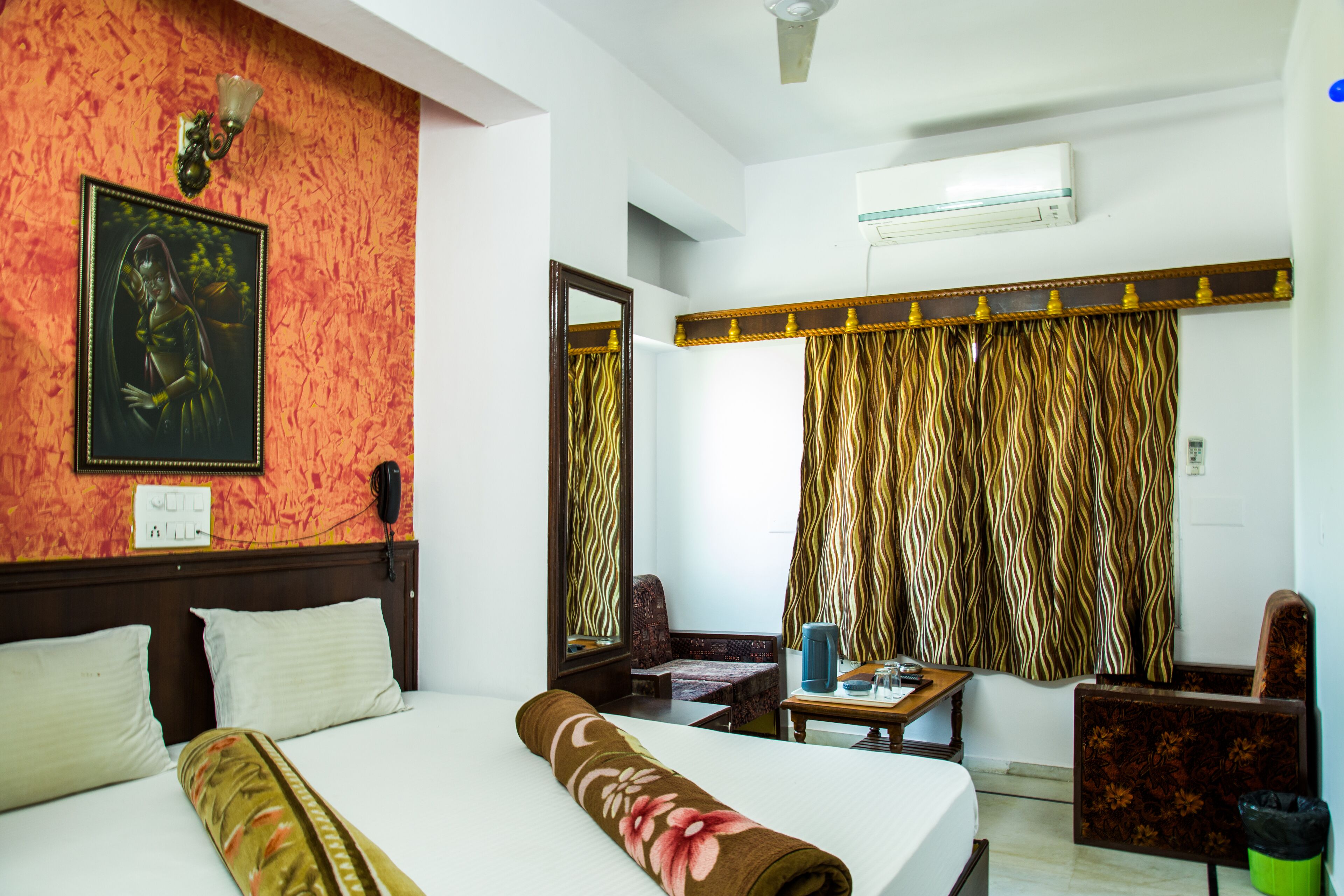 A hotel room with a bed, a chair, a table, a telephone, and curtains.