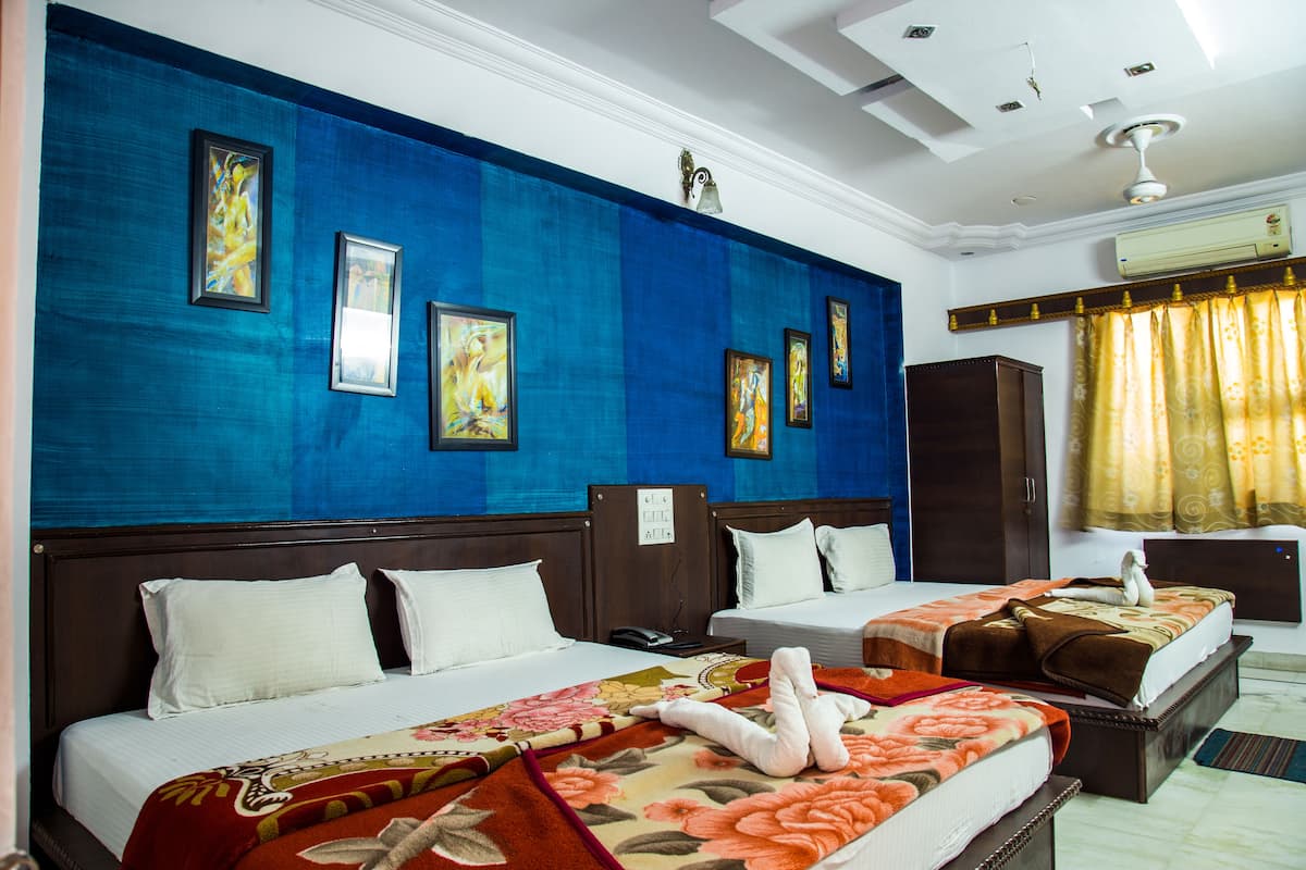 A hotel room with two beds, a large blue accent wall, and framed artwork.