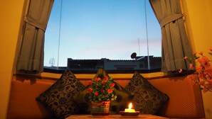 A window with curtains, a table with a candle, and a potted plant. - Your Place Inn (Karon)