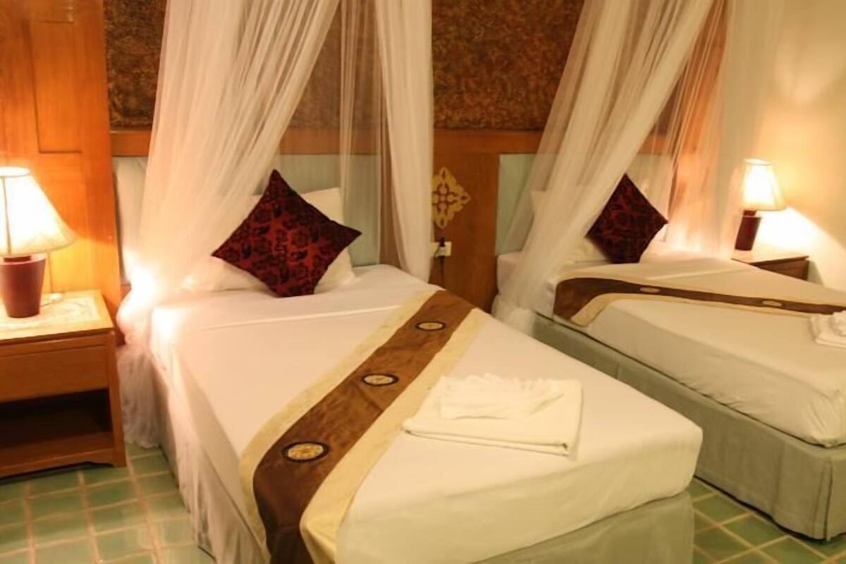 A room with two beds, each with a canopy and a bedside lamp.