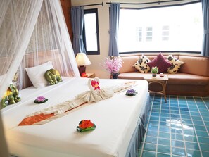 Una habitación de hotel con cama, sofá, mesita de noche y ventana con cortinas.