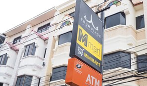Un edificio con un letrero que dice 'Your Place' y 'Minimart' en la planta baja, y un anuncio de cajero automático en el nivel inferior.