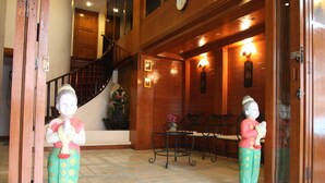 A wooden interior with a staircase, a bench, and two statues. - Your Place Inn (Karon)