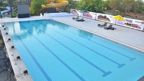 Una piscina con baldosas azul cristalina, sillas de descanso y un tobogán al fondo.