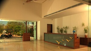 Un vestíbulo amplio con mostrador de recepción, ventanas grandes y plantas de interior.