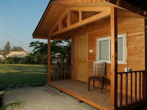 Une cabane en bois avec une véranda, une porte et une fenêtre.