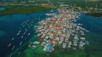Vista aérea de un asentamiento costero con numerosos barcos amarrados a lo largo de la orilla y un denso conjunto de edificios pequeños y adosados.