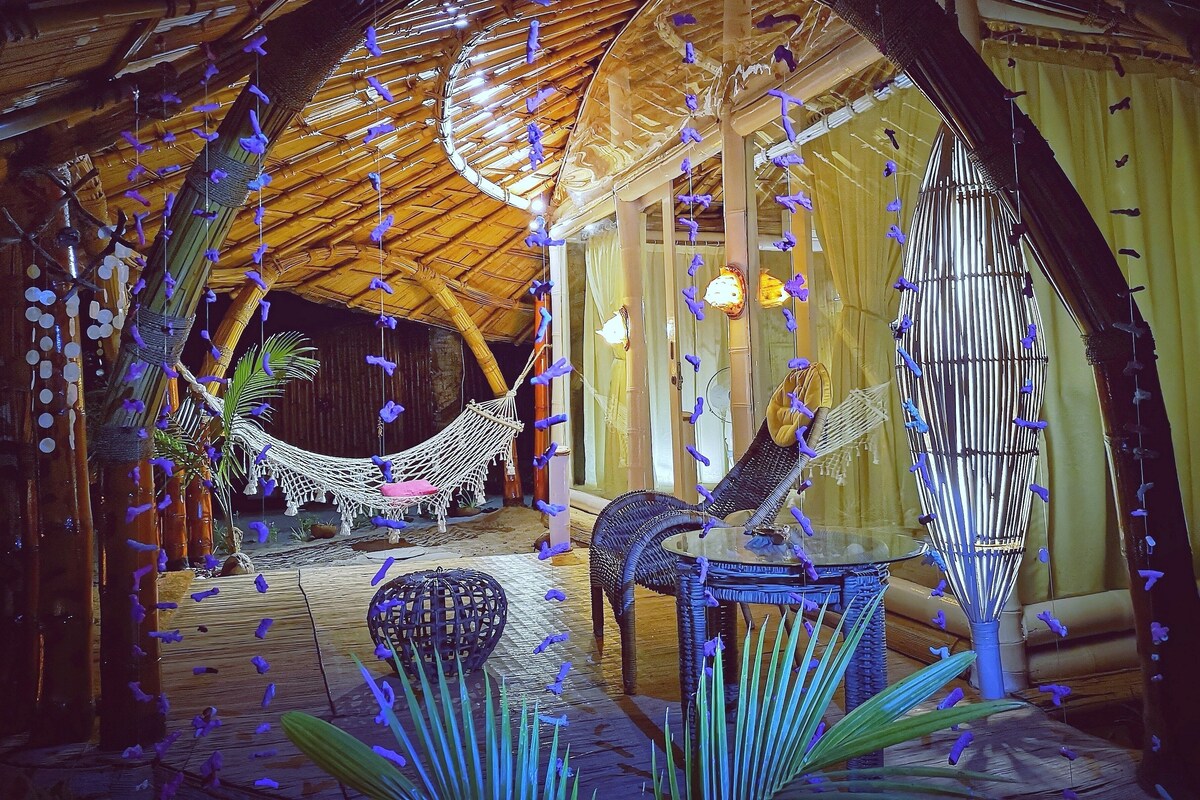 Une pièce avec un hamac, des meubles en osier et une table en verre.