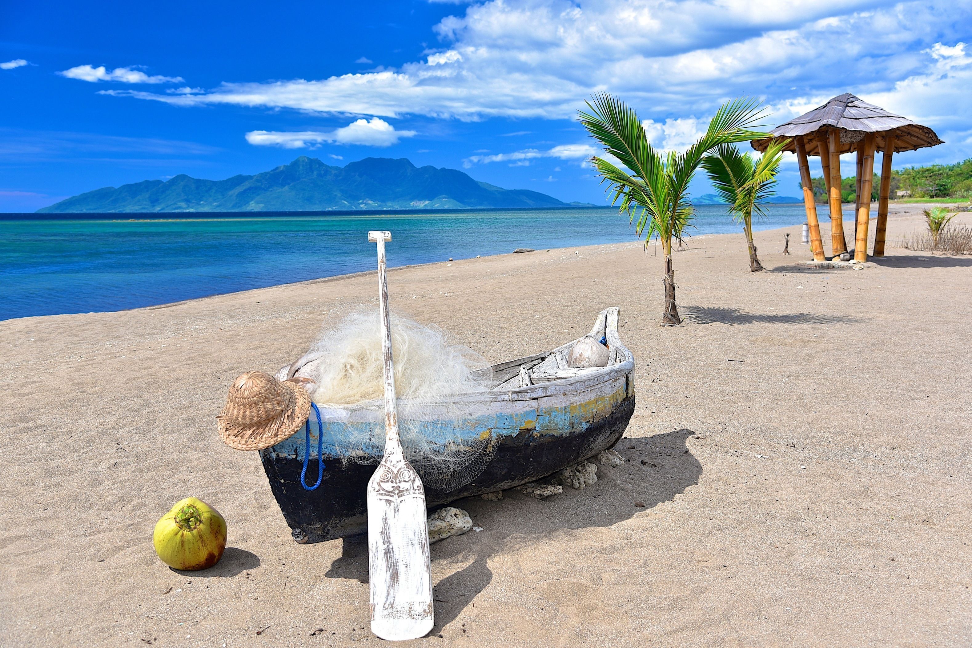 A boat on a sandy beach with a mountain in the background.