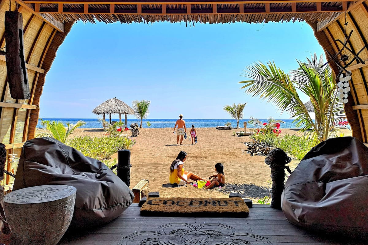 Une vue sur la plage depuis un espace abrité doté d’un plancher en bois et d’un tapis décoratif.