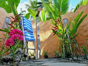 Un jardin tropical agrémenté d’un mur rustique, d’une structure en bois et de diverses plantes.