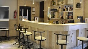 A bar area with a counter, stools, and shelves stocked with bottles. - Dimitris Paritsa Hotel (Kos)