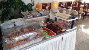 A buffet with various food items including bread, eggs, and meats, in a well-lit dining area with tables and chairs. - Dimitris Paritsa Hotel (Kos)
