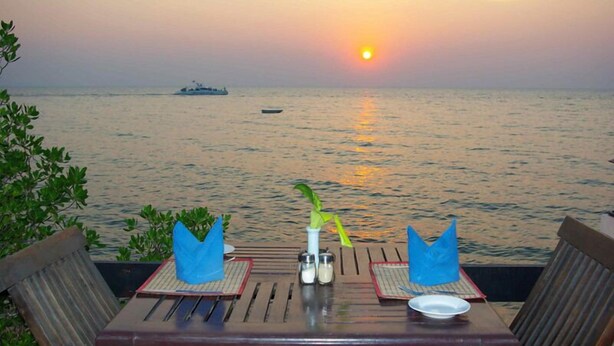 A table set for two with a view of the sunset over the ocean. - Sea Falcon Hotel (Sattahip)
